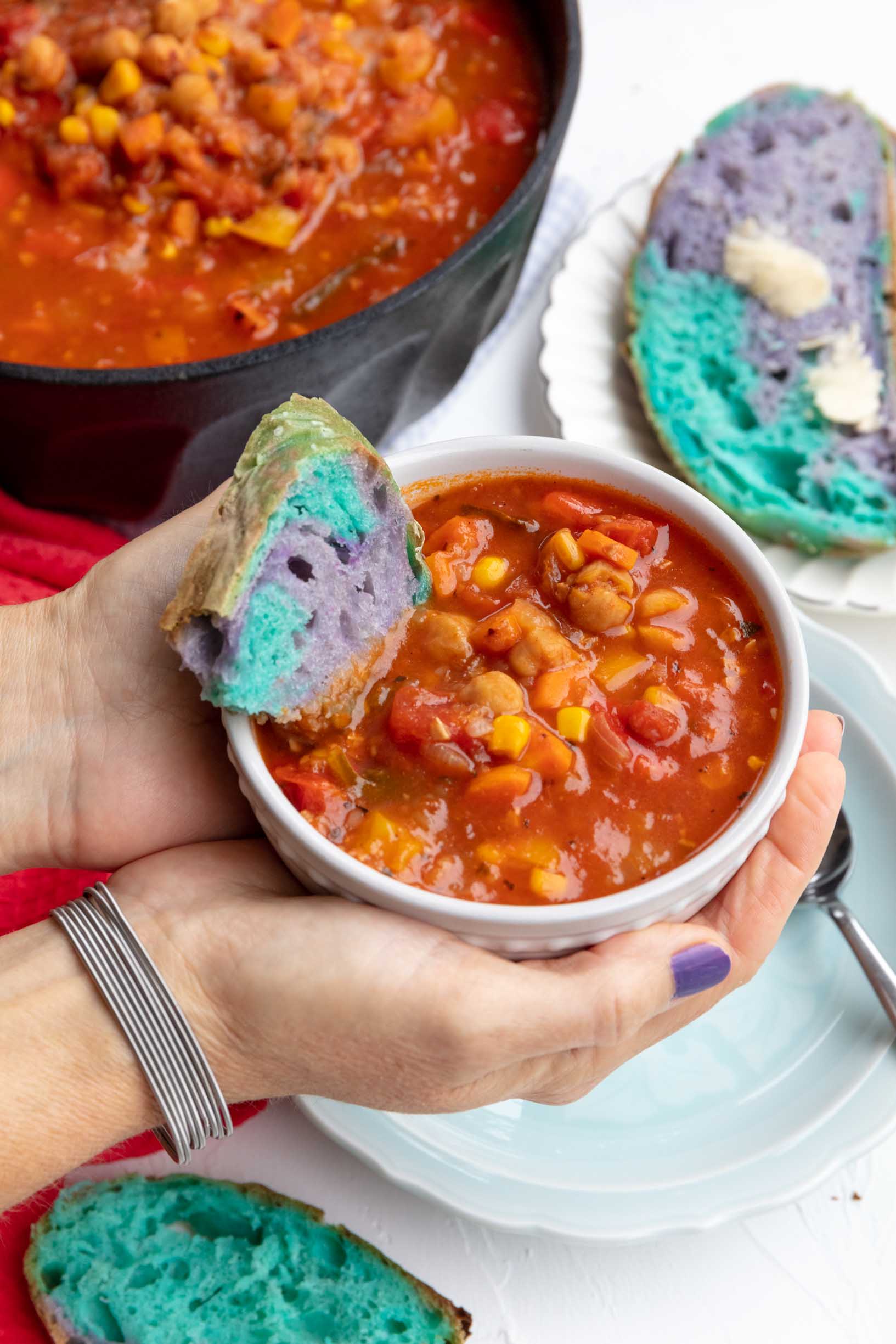 Robin holding a bowl of Panera’s 10 vegetable soup with a piece of colorful bread in it