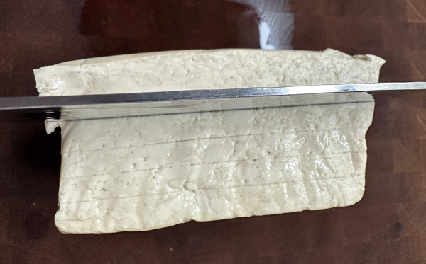 scoring the tofu to make sure the slices are an even thickness